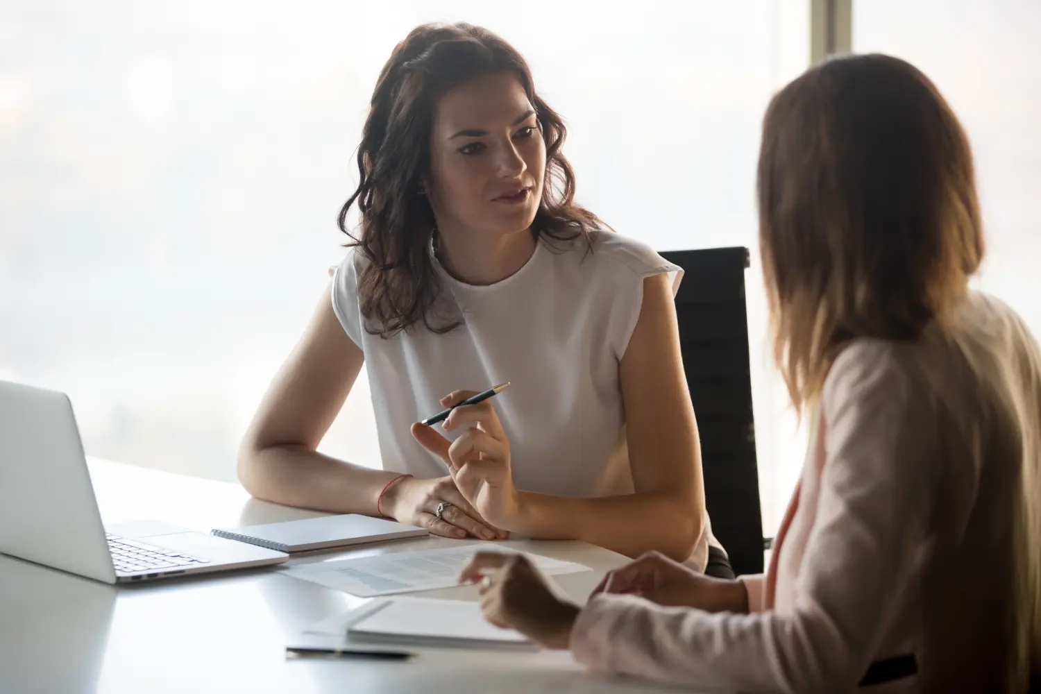 Zwei unterschiedliche, seriöse Geschäftsfrauen diskutieren gemeinsam über ein Geschäftsprojekt.